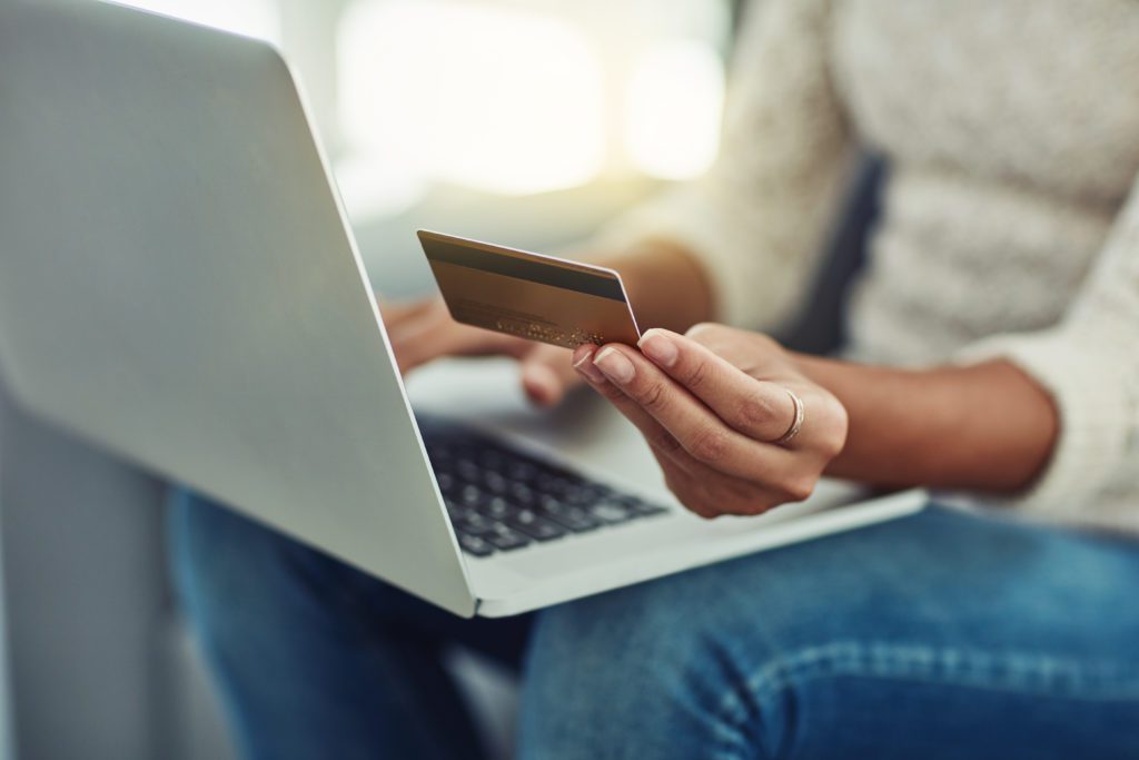 A woman using a laptop to make a purchase with her credit card.