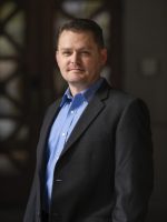 A man in a suit standing in front of a door.